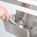 A hand using a metal Regency ice cream dipper well in a sink.