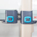 A close-up of two gray and blue plastic clips on a metal MetroMax Q shelving unit.