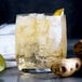 A glass of Narvon ginger ale with ice, ginger root, lime, and lemon slices.