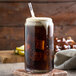 A glass of Narvon Old Fashioned Root Beer with ice and a straw.