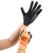 A pair of hands wearing orange and black Cordova Cor-Tex gloves.