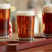 A tray with three Libbey Esquire side water/tasting glasses of beer on a table in a bar.