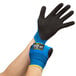 A pair of extra large blue gloves with black palm coating on a person's hands.