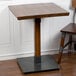 A Lancaster Table & Seating wooden dining table with a metal base.