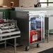 An Avantco stainless steel back bar refrigerator with beer bottles inside.
