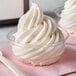 A close up of a clear plastic dessert cup filled with swirled white ice cream.