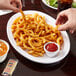 A Carlisle white oval platter with fries, ketchup, and a drink on it.