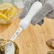 A person using a Choice Boston Style Oyster Knife to shuck oysters on a counter.