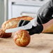 A 7-inch offset serrated edge bread knife with a white handle being used to slice a bread roll.