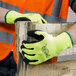 A person wearing Cordova Hi-Vis green gloves holding a piece of wood.
