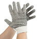 A hand wearing a Cordova white work glove with black PVC dots on the palm.