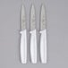 Three white Choice paring knives with white handles.