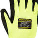 A close up of a Cordova Monarch heavy duty work glove with black foam latex coating and yellow and black stripes on a white background.