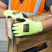 A person wearing Cordova Monarch heavy duty work gloves while holding a piece of wood.