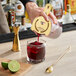 A person using an Acopa cocktail stirring glass to pour a drink with ice cubes.