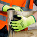 A person wearing Cordova Hi-Vis green safety gloves holding a piece of wood.