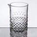 A clear glass cocktail stirring glass with a textured diamond pattern and a spout.
