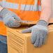 A person wearing Cordova gray and orange safety gloves holding a box.