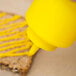 A close up of yellow mustard being poured from a yellow Choice squeeze bottle.