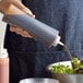 A woman using a Choice clear squeeze bottle to pour pink sauce onto a bowl of green salad.