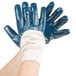 A pair of hands wearing blue Cordova warehouse gloves with white jersey lining.