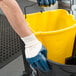 A hand in a Cordova blue nitrile glove holding a yellow bucket.