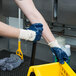 A person wearing Cordova blue gloves holding a yellow basket.