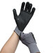 A pair of hands wearing gray and black Cordova Conquest Plus gloves with nitrile dots.