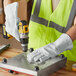 A man wearing Cordova gray leather welder's gloves using a drill on metal.