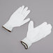 A pair of Cordova white nylon gloves with white polyurethane palms on a gray surface.