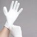 A person wearing Cordova white nylon gloves with white polyurethane palm coating.