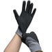 A pair of Cordova Conquest gray and black gloves with black foam nitrile palms being worn on a pair of hands.
