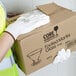 A person wearing Cordova white gloves with white polyurethane palm coating holding a box.
