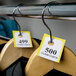 Choice Yellow Paper Coat Room Check Tickets on a rack of clothes.