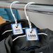 A close-up of blue paper tickets on a coat rack with clothes hanging on it.