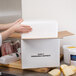 A person holding a Nordic insulated shipping box with a white piece of cardboard inside.