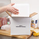 A hand opening a Nordic insulated shipping box with food on a counter.