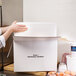 A person holding a Nordic insulated shipping box with a white container inside.