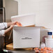 A person packing a Nordic insulated shipping box on a counter.