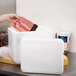 A hand putting meat in a Nordic insulated white cooler.