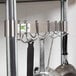 A Regency stainless steel leg mounted pot rack with hooks holding utensils.