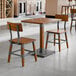 A rustic walnut finish solid wood table with a live edge and two matching industrial-style chairs.