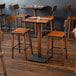 A Lancaster Table & Seating live edge wood bar height table with two bar chairs.