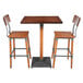 A Lancaster Table & Seating live edge wood bar table with two bar chairs.