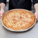 A man holding a pizza with a Solut clear plastic lid.