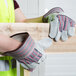 A person wearing Cordova canvas and leather work gloves holding a piece of wood.