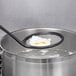 A black Matfer Bourgeat skimmer spoon with a fine mesh over a pot of food.