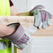A person wearing Cordova canvas work gloves holding a piece of wood.