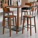 A square rustic walnut finish bar height table with four matching industrial-style bar stools.