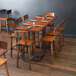 A Lancaster Table & Seating bar height table with wooden chairs in a restaurant dining area.